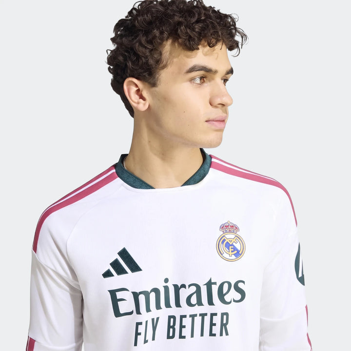 Close-up of a male model wearing the white Real Madrid 25/26 long-sleeve home jersey with team crest and sponsor logo.