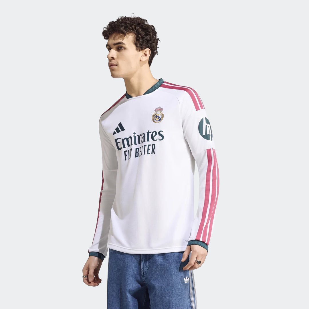 Male model wearing a white Real Madrid 25/26 Long Sleeve Home Jersey, featuring team crest and sponsor logos, paired with