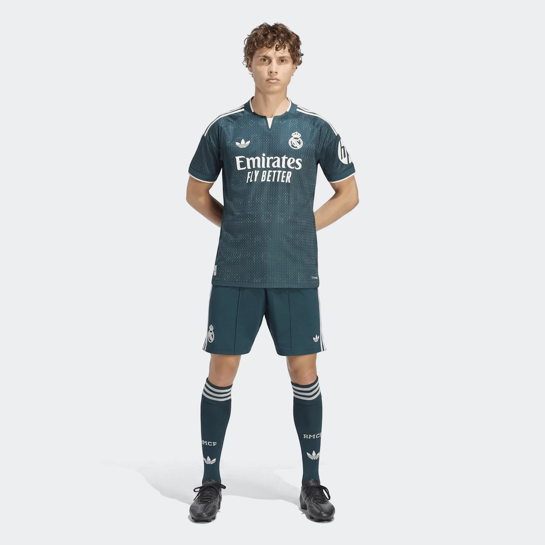 Male model wearing a dark green Real Madrid 26/27 Away Authentic Jersey, matching shorts, and socks, facing forward.