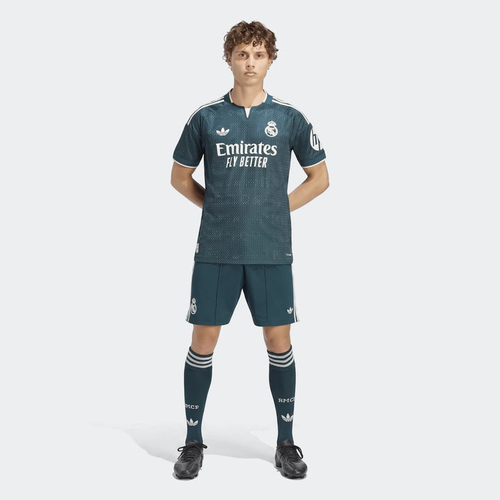 Male model wearing a dark green Real Madrid 26/27 Away Authentic Jersey, matching shorts, and socks, facing forward.
