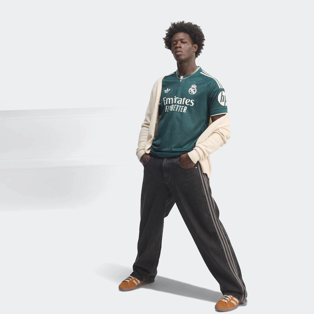 Real Madrid 26/27 Away Authentic Jersey in green, worn by a male model, featuring sponsor logos and club crest.