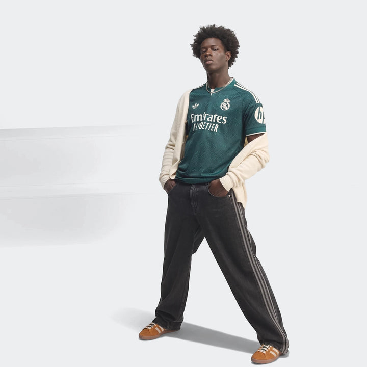 Real Madrid 26/27 Away Authentic Jersey in green, worn by a male model, featuring sponsor logos and club crest.