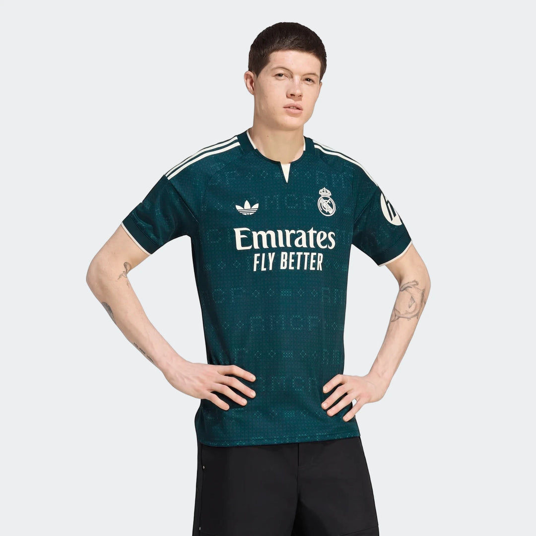 Male model wearing a dark green Adidas Real Madrid 26/27 away jersey with white stripes and sponsor logos, captured in a