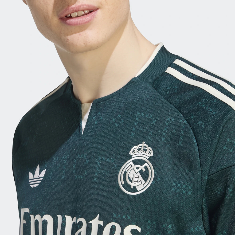 Close-up of a man wearing a dark green Real Madrid 26/27 Away Jersey, featuring white Adidas stripes and the embroidered