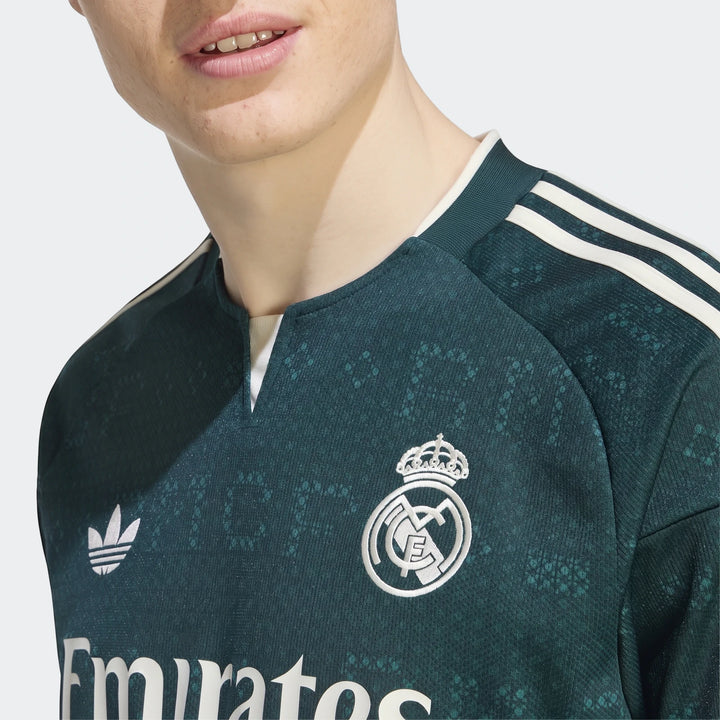 Close-up of a man wearing a dark green Real Madrid 26/27 Away Jersey, featuring white Adidas stripes and the embroidered