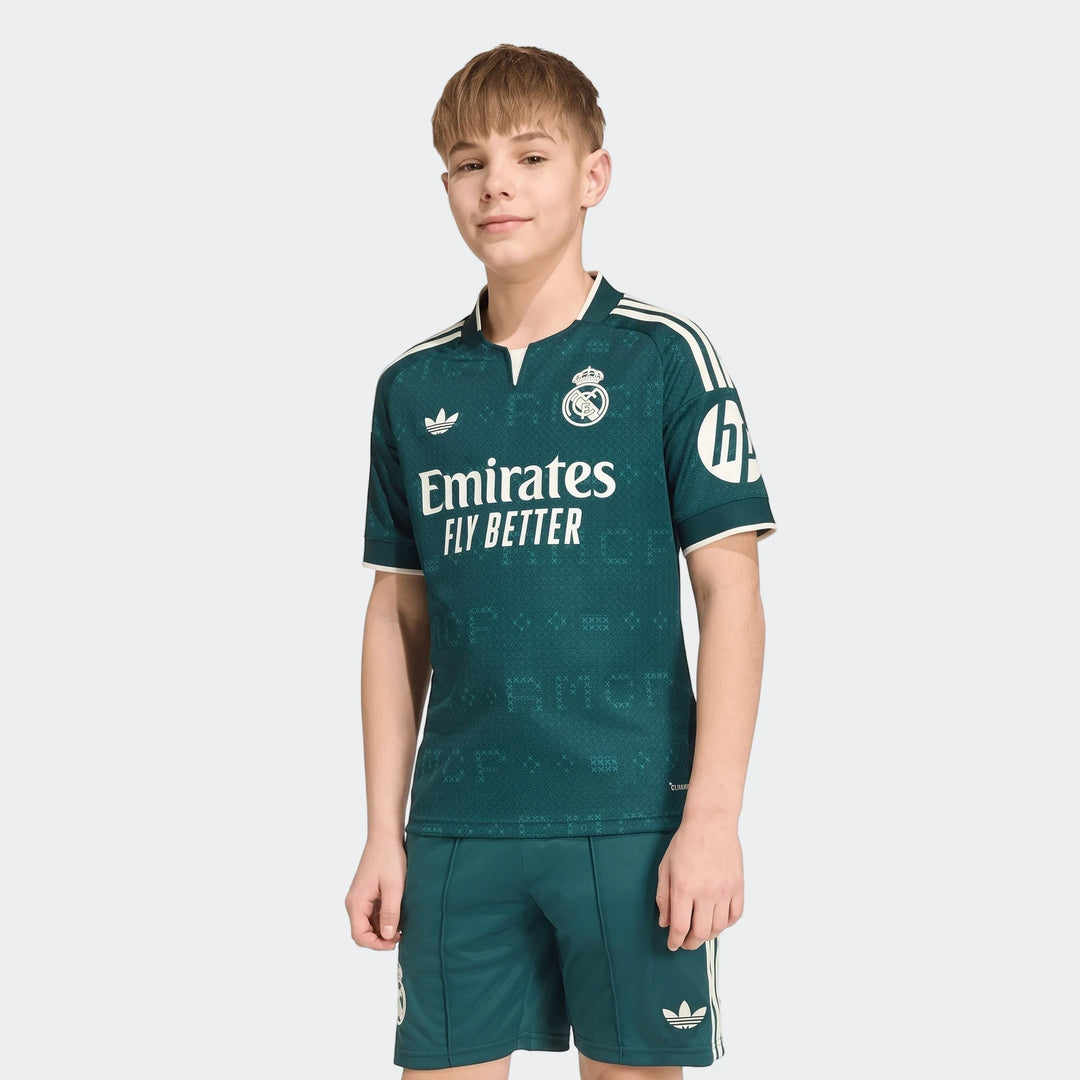 Young boy wearing a green Real Madrid 26/27 Away Jersey and matching shorts with white Adidas logos and team crest.