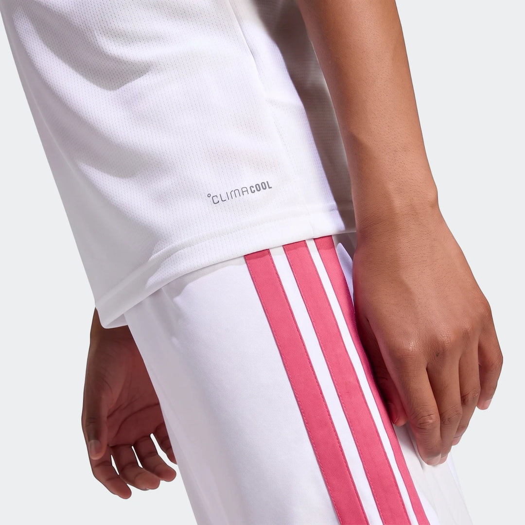 Close-up of a child wearing a white Real Madrid 26/27 Home Jersey with mesh Climacool fabric and white shorts featuring pink