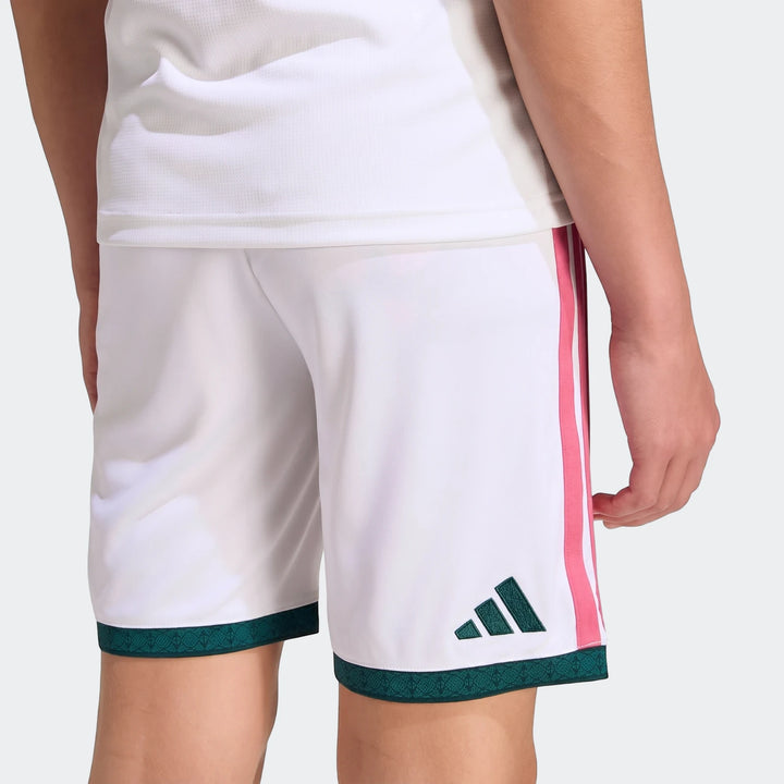 White Real Madrid 26/27 home shorts for kids with pink three-stripes and a dark green patterned hem, shown from a rear view.