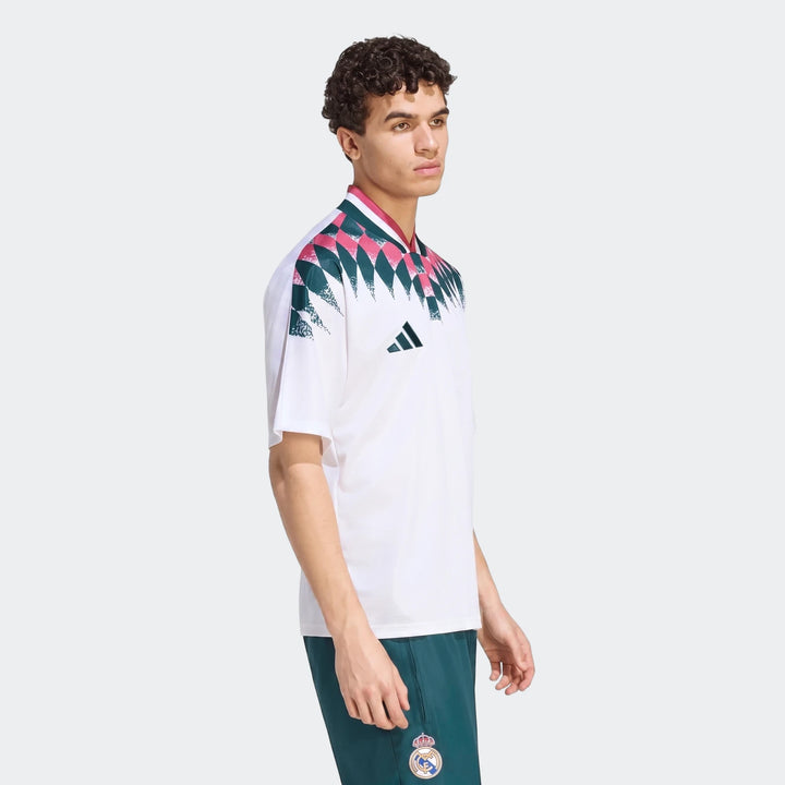 Male model wearing a white Real Madrid Street Jersey with a teal and pink geometric pattern and dark green shorts.