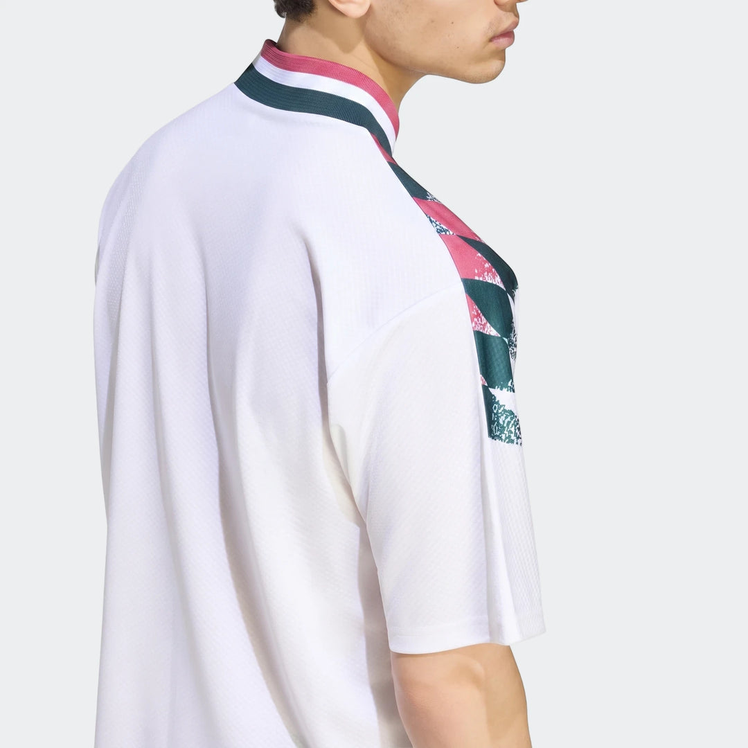 Close-up of a man wearing a white Real Madrid Street Jersey with green and pink geometric patterns and collar details.