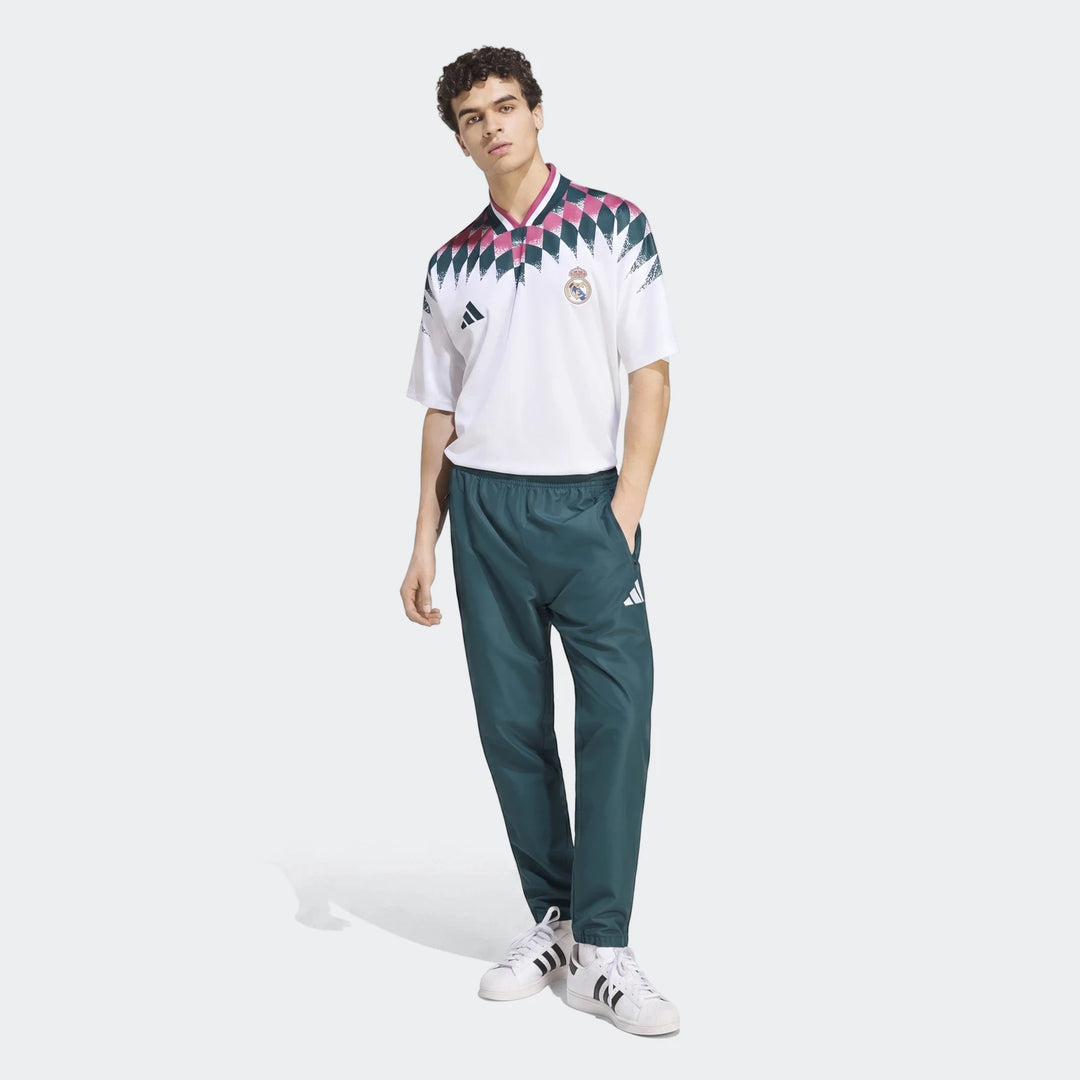 Real Madrid Street Jersey in white with pink and green patterns, worn by a male model in a full-body shot, paired with dark