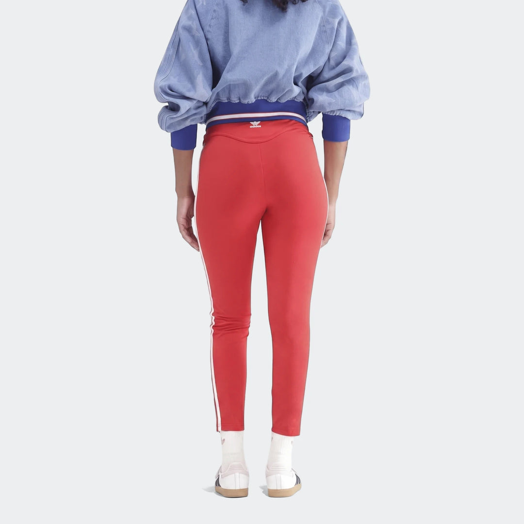 Rear view of a person wearing red Adidas 3-Stripes cotton leggings with white side stripes, paired with a blue denim jacket