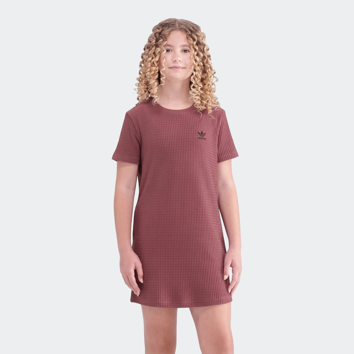 A young person models a reddish-brown short-sleeved Adidas waffle dress, showcasing its texture and casual fit.