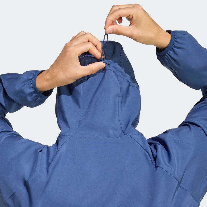 Blue Run Essentials Jacket from the back, with a person adjusting the hood drawstring.