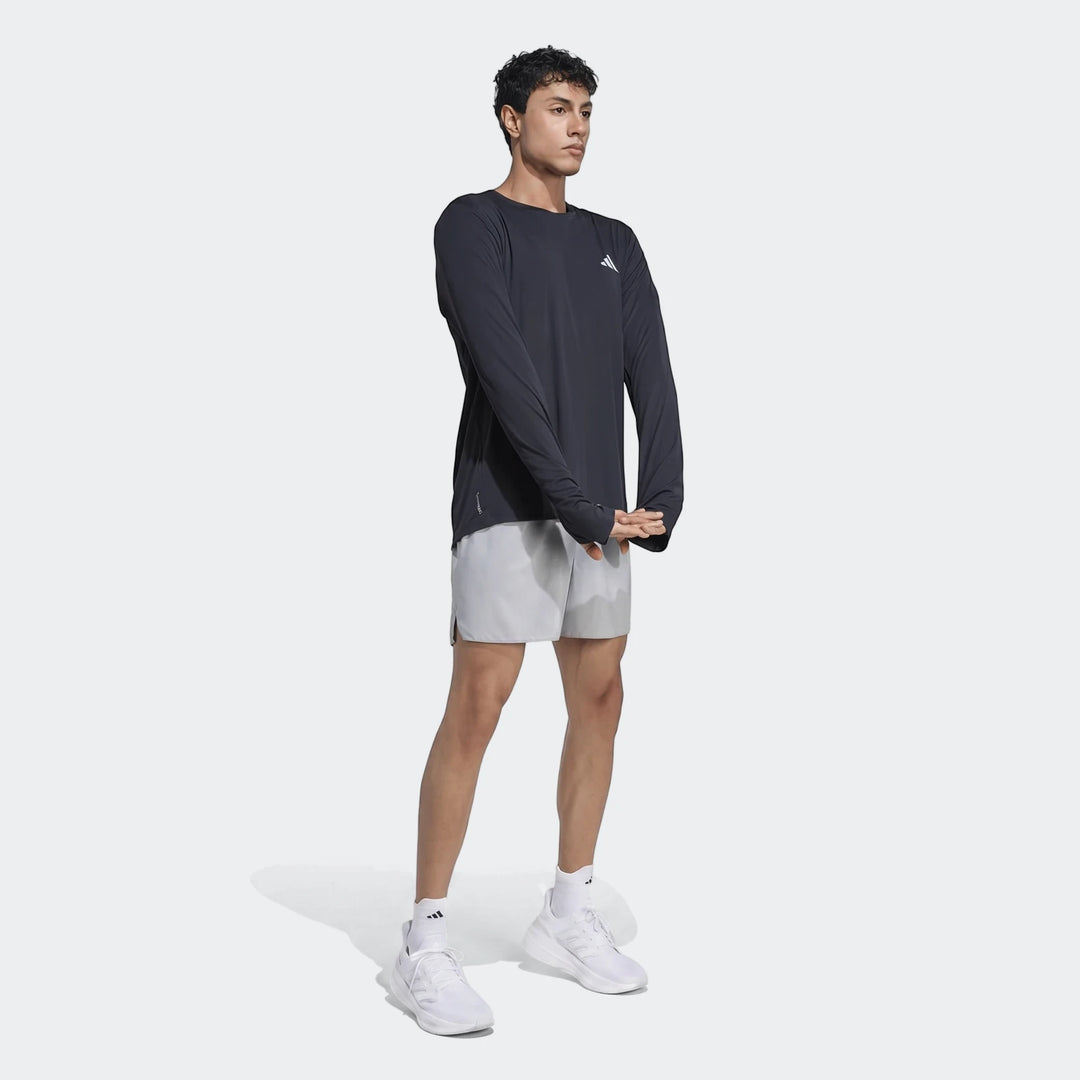 Dark gray Run Essentials Long Sleeve Top worn by a male model in a full-body shot, paired with light gray shorts and white