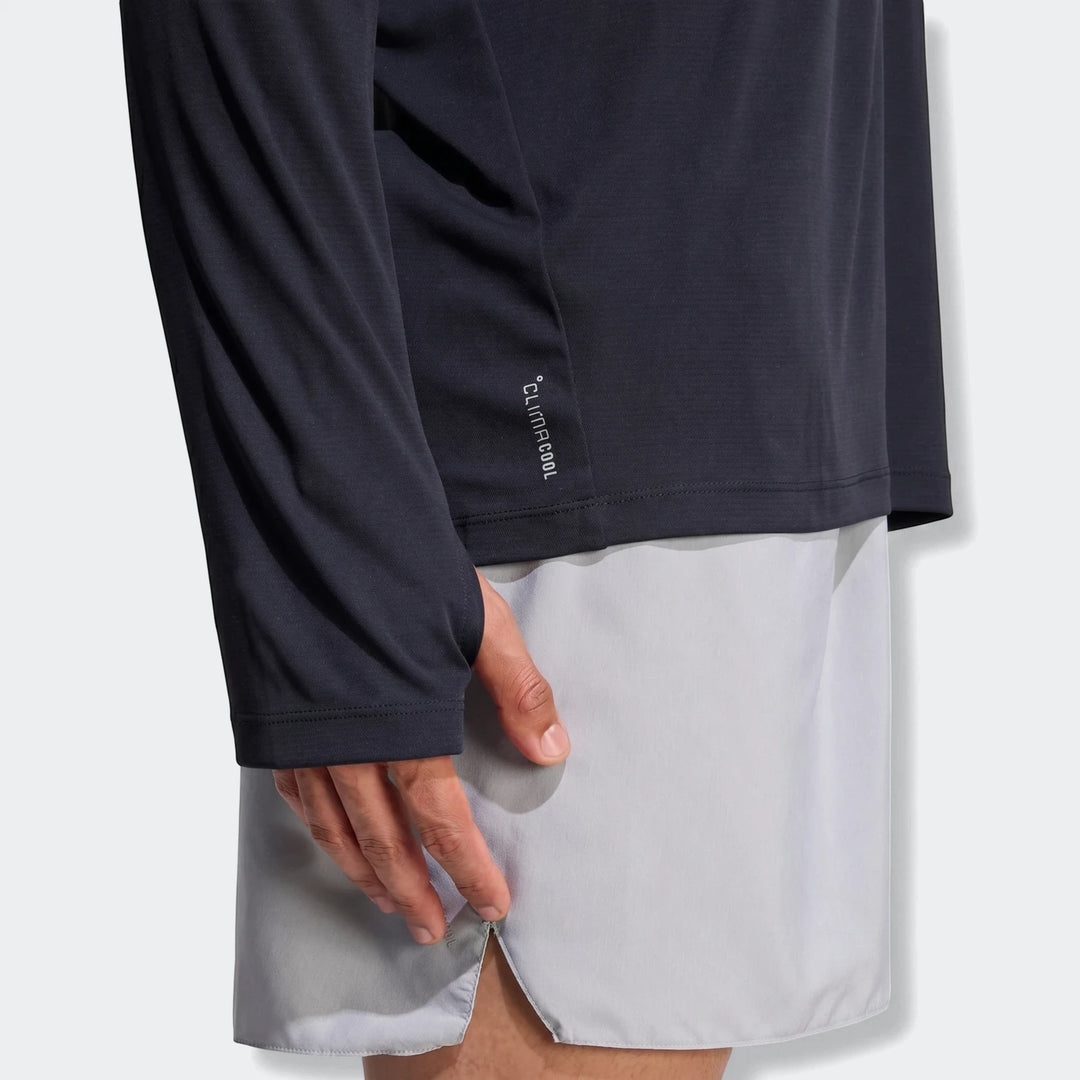 Side view of a person wearing a dark long sleeve Run Essentials Long Sleeve Top with a CLIMACOOL logo and light grey shorts.