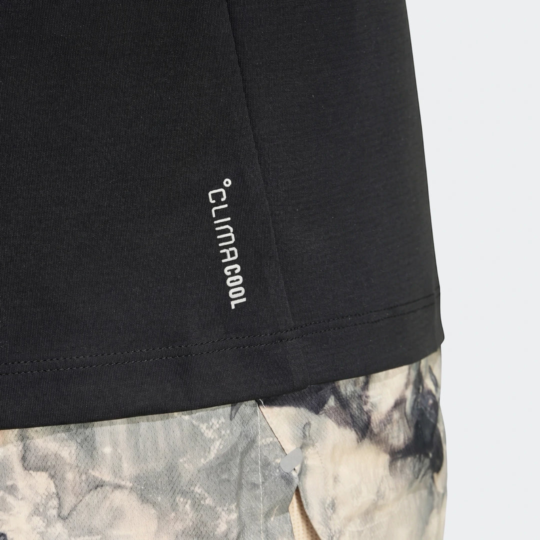 Black Run Essentials T-Shirt with white CLIMACOOL logo, shown worn with abstract patterned shorts, close-up view.