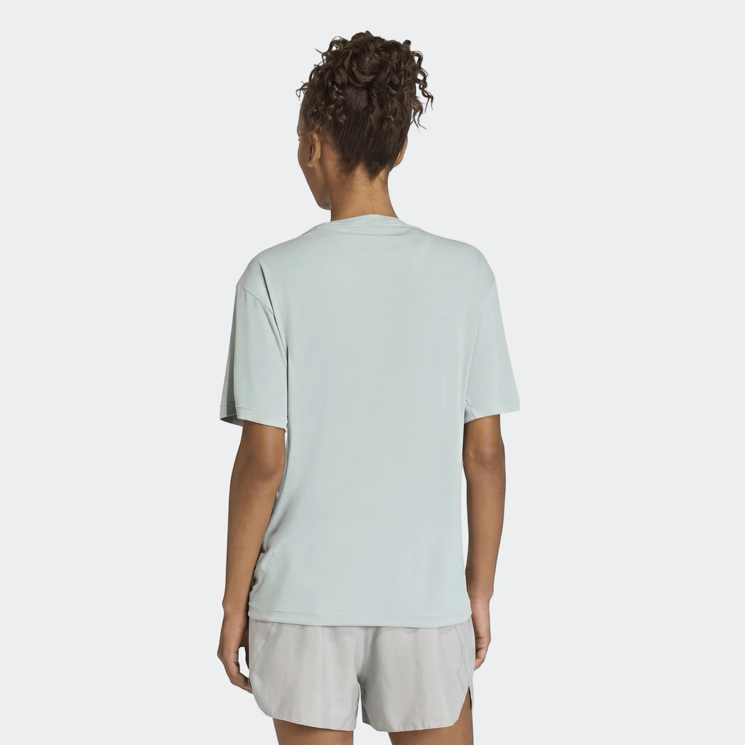 Woman from the back wearing a light green Run Essentials T-Shirt and grey athletic shorts with curly hair tied up.