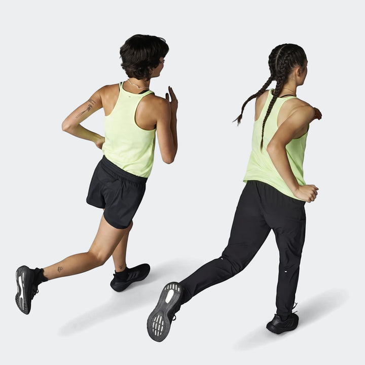 Two women running, one in black Run It Tko Joggers, another in black shorts, both wearing neon lime green tops.