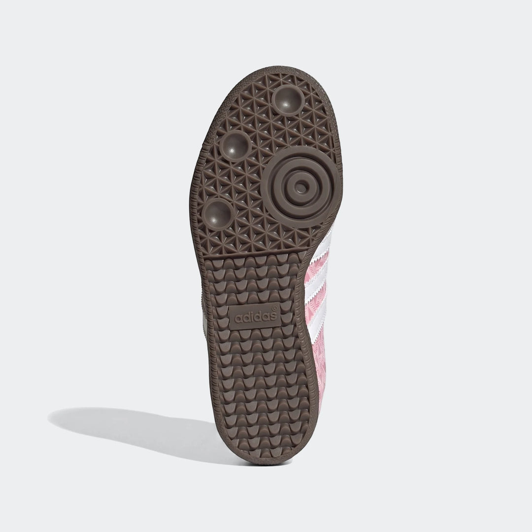 Samba Og Kids shoes with a pink upper and white stripes, showcasing the brown rubber sole and tread pattern from a bottom