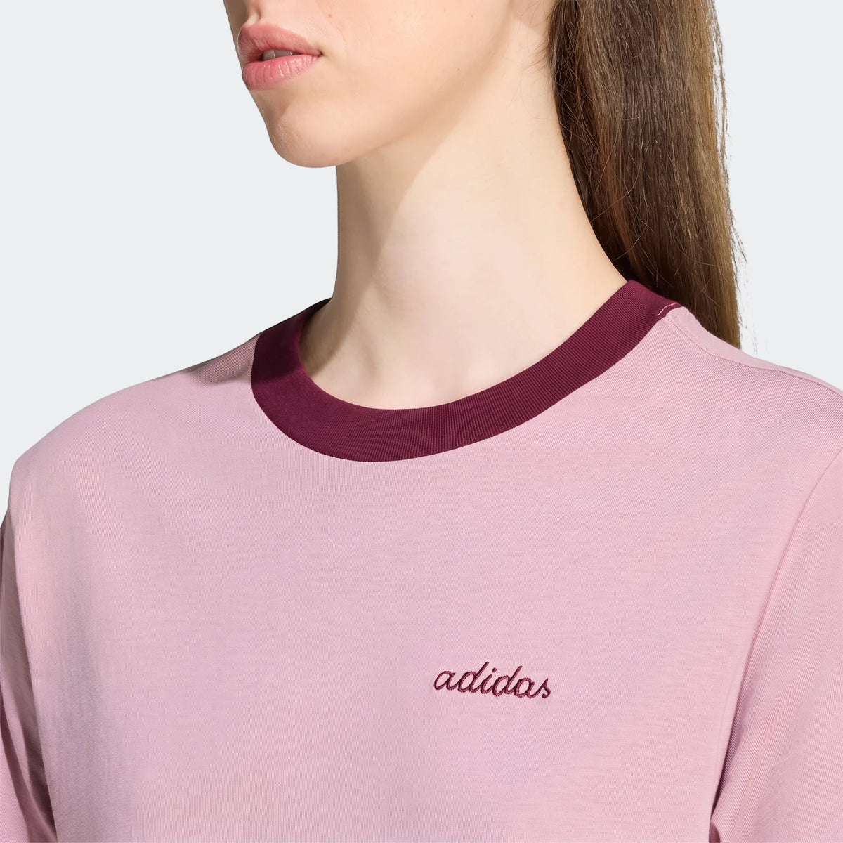 Close-up of a light pink Seasonal Essentials Colorpop T-Shirt with a maroon ringer collar and embroidered adidas graphic,