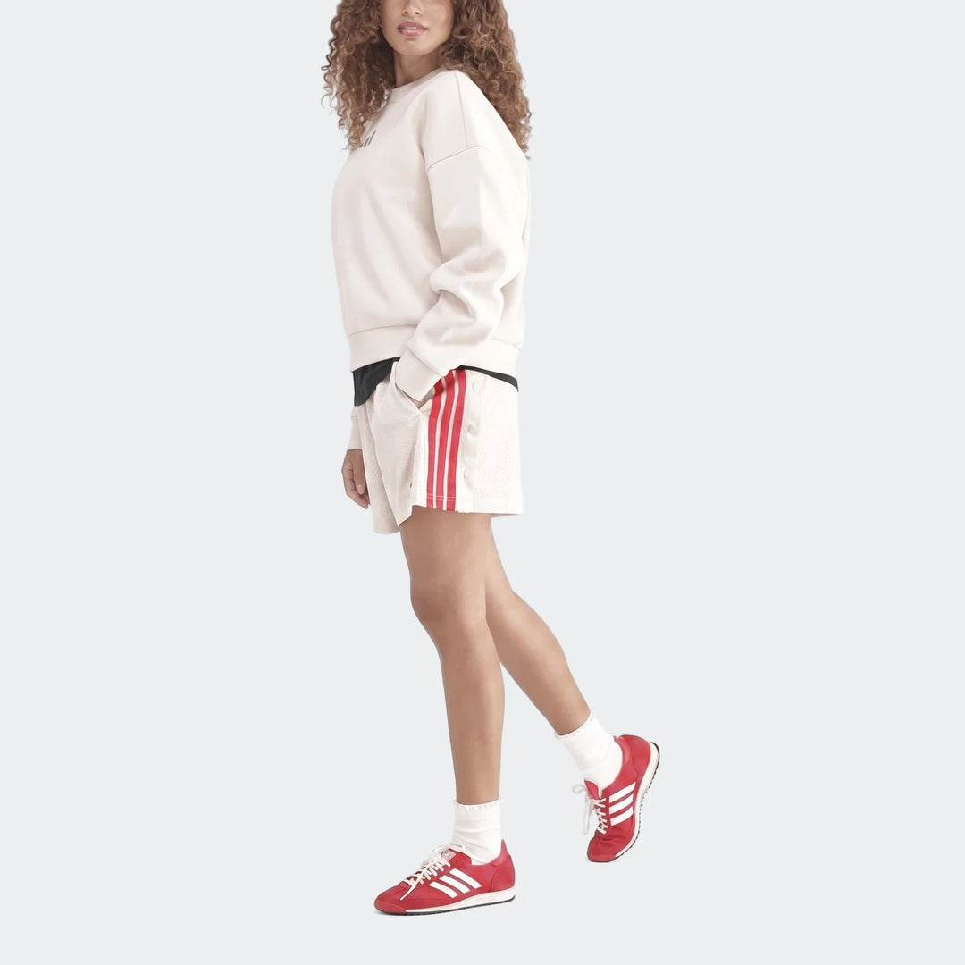 Female model wearing a cream Slim Fleece Crew Sweatshirt, white shorts with red side stripes, and red sneakers. Full body