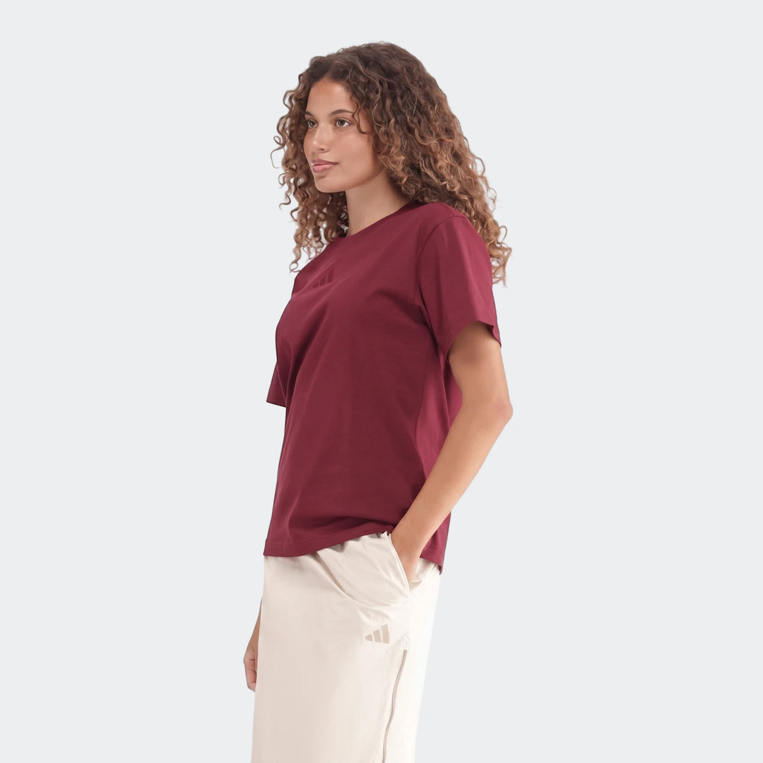 Female model wearing a burgundy Slim Single Jersey T-Shirt and light-colored shorts, shown from the waist up in a side