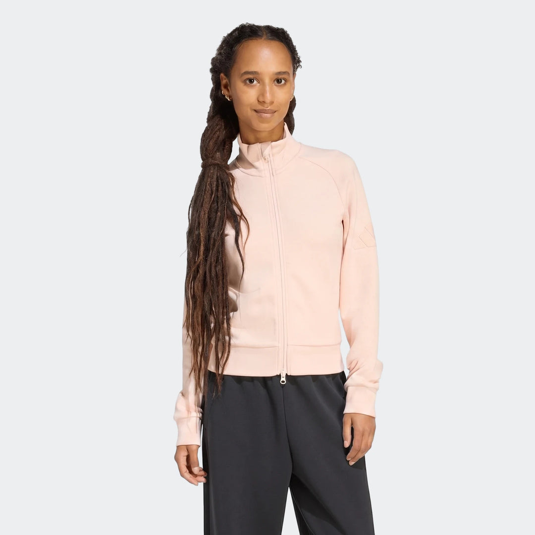 Woman wearing a light pink Soft Luxe Slim Track Top with dark pants, front view, showcasing the design.