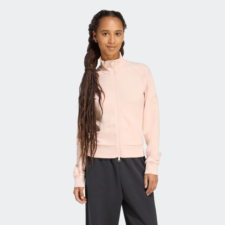 Woman wearing a light pink Soft Luxe Slim Track Top with dark pants, front view, showcasing the design.