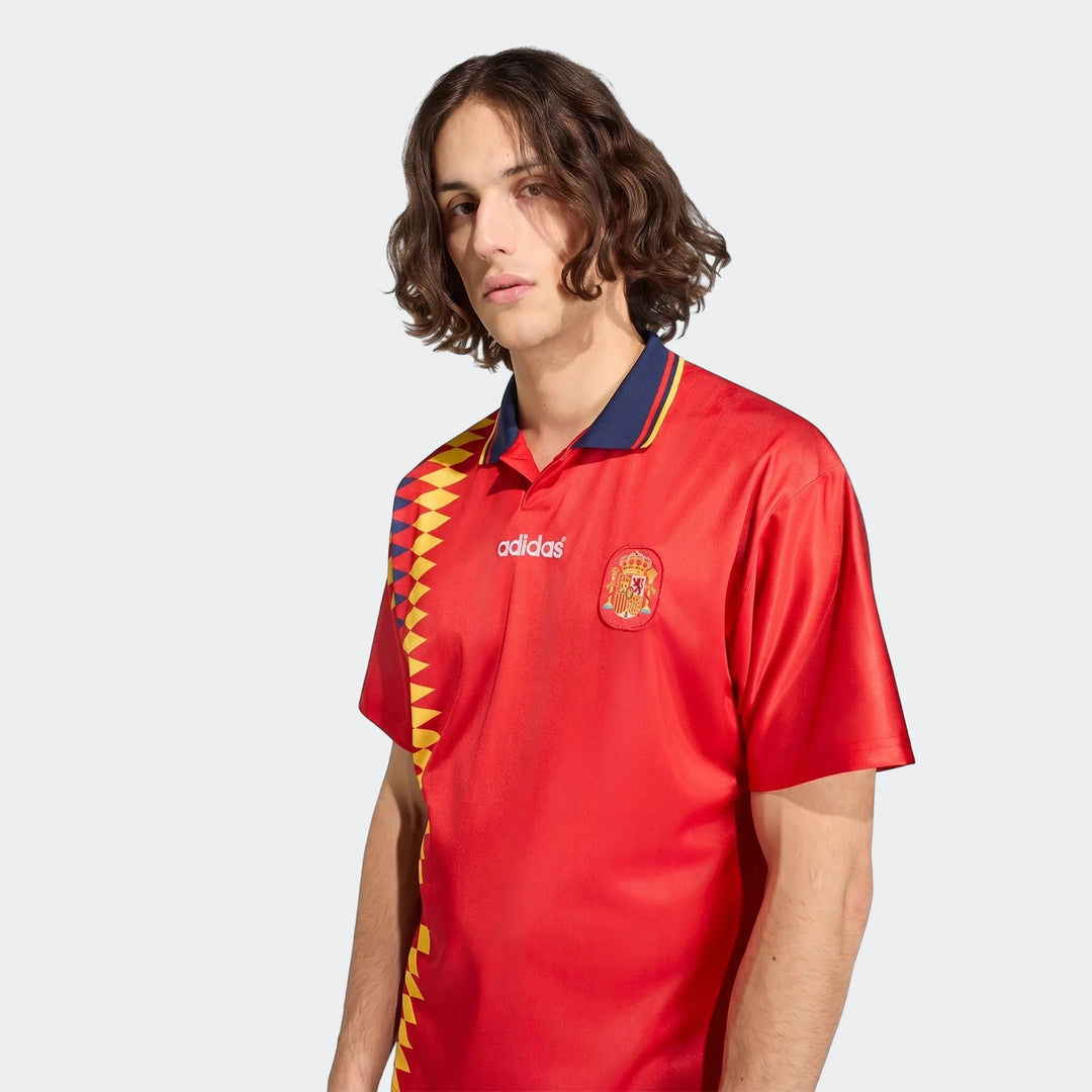 Male model wearing a red Spain 1994 Retro Home Jersey, featuring classic Adidas branding and team crest, front view.