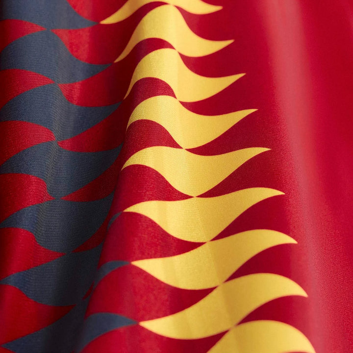 Close up of the Spain 1994 Retro Home Jersey, featuring wavy red, dark blue, and yellow patterns on draped fabric.