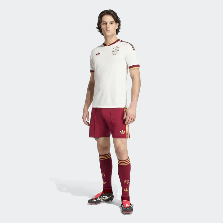 Male model wearing the white and maroon Spain 25/26 Authentic Away Jersey kit with matching shorts, socks, and cleats, full