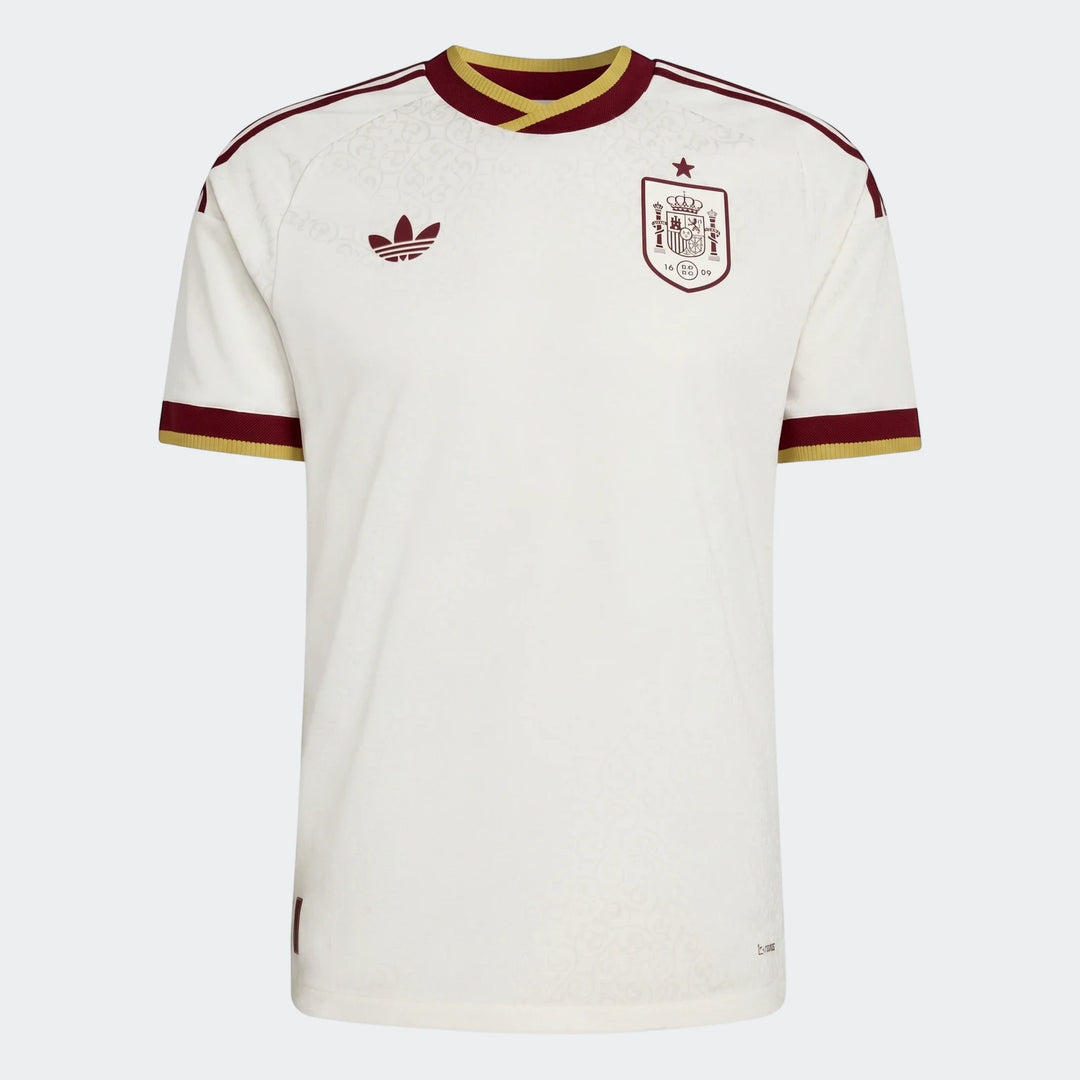 Off-white Spain 25/26 Authentic Away Jersey with maroon and gold trim, featuring Adidas logo and team crest, displayed flat.