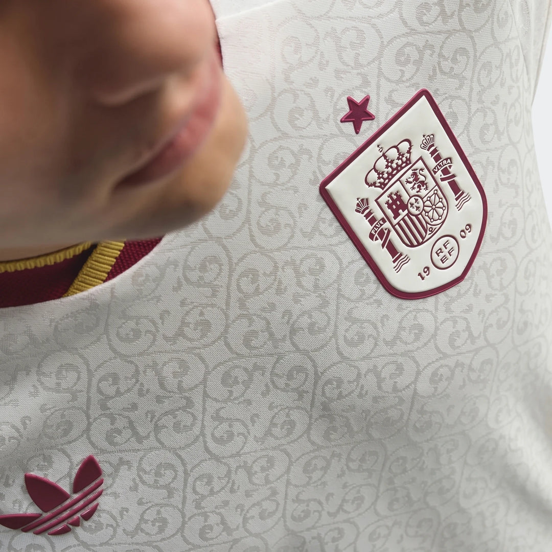 Close-up of a Spain 25/26 Authentic Away Jersey, white with maroon national team crest and Adidas logo, worn by a model.