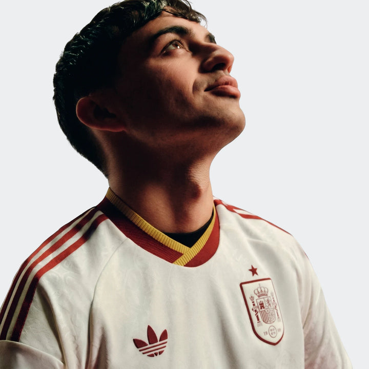 Close-up of a male model wearing the Spain 25/26 Authentic Away Jersey, featuring a white body with red and yellow details.