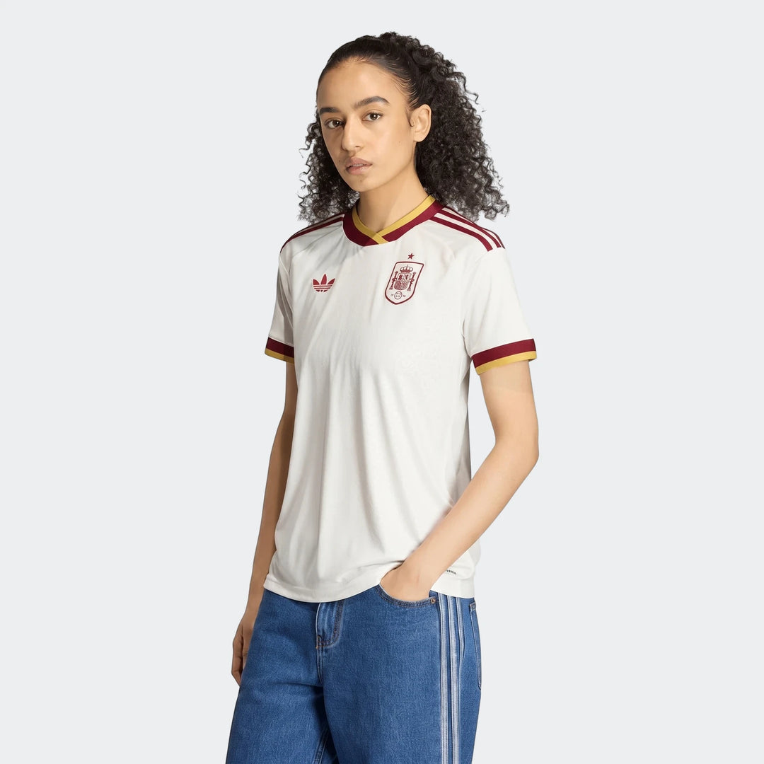Women's Spain 25/26 Away Jersey in white with maroon and gold trim, featuring Adidas and team logos, worn by a model.