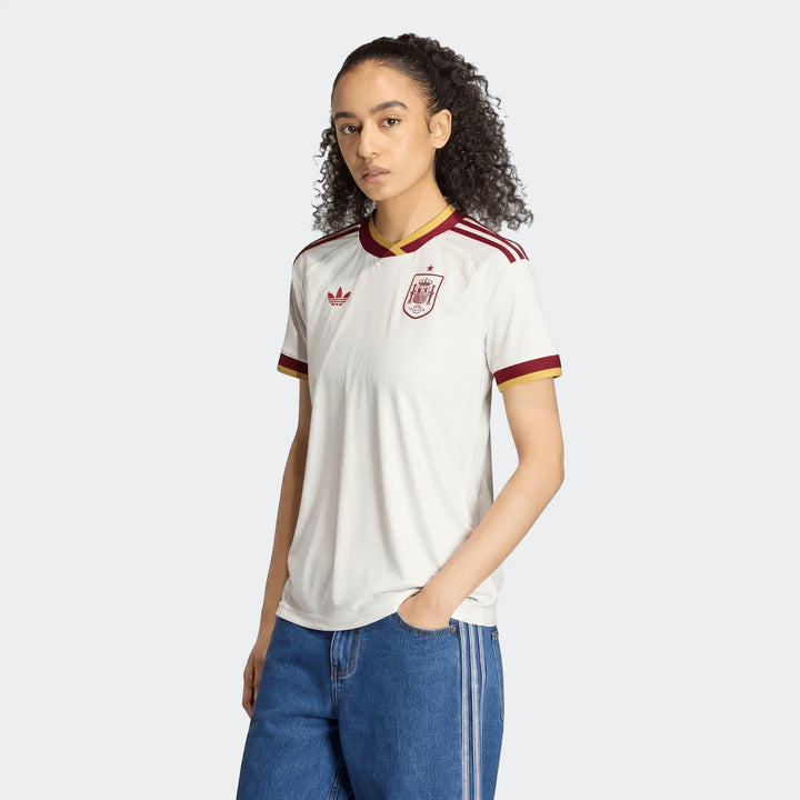 Women's Spain 25/26 Away Jersey in white with maroon and gold trim, featuring Adidas and team logos, worn by a model.