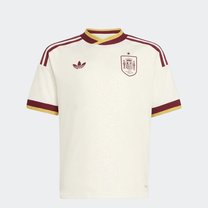 Spain 25/26 Away Youth Jersey, an off-white short-sleeve football shirt with maroon and yellow details, shown front view.