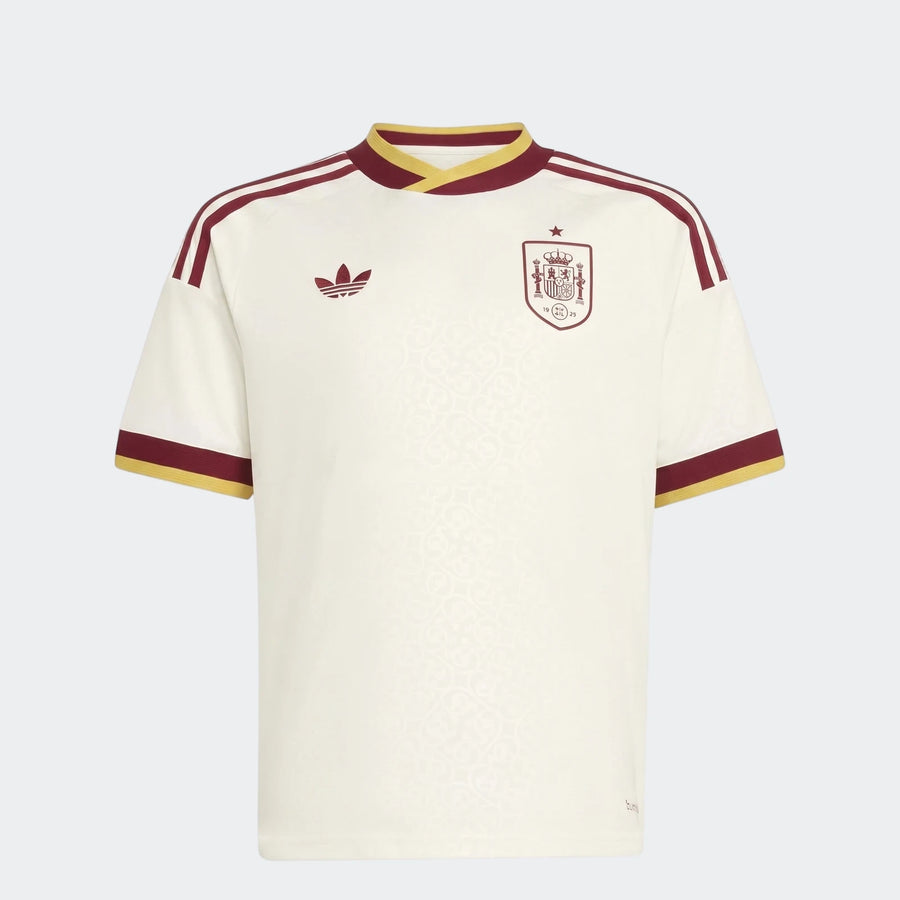 Spain 25/26 Away Youth Jersey, an off-white short-sleeve football shirt with maroon and yellow details, shown front view.