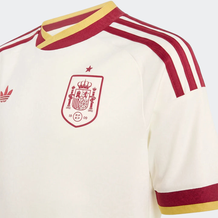 Close-up of a white Spain 25/26 Away Youth Jersey featuring red and yellow collar and sleeve details, Adidas logo, and