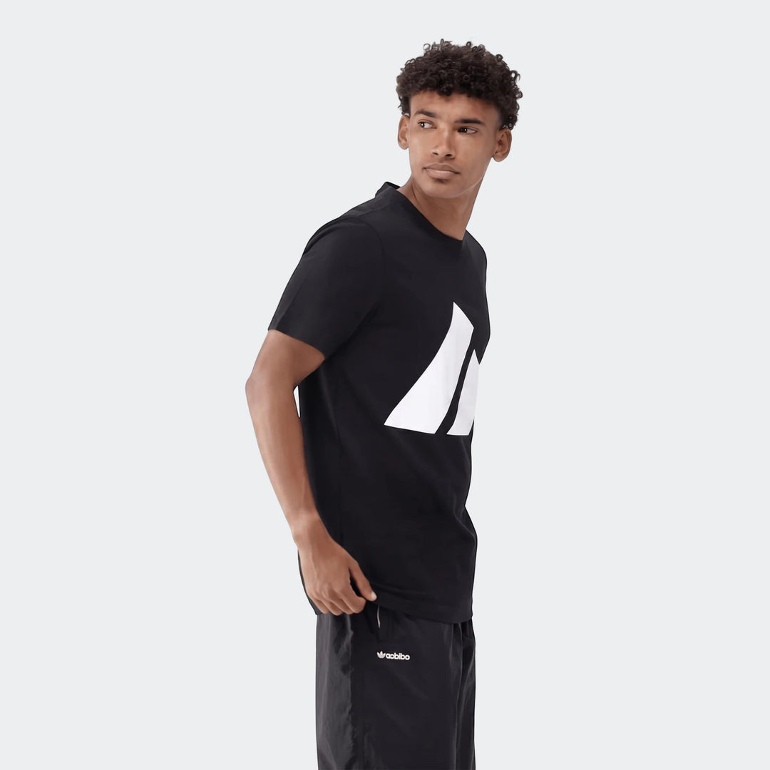 Young man modeling a black Sportswear Badge Of Sport T-Shirt with a prominent white logo and black shorts.