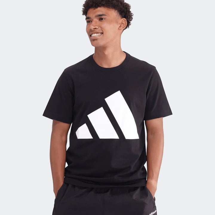 Male model wearing a black Sportswear Badge Of Sport T-Shirt with a white Adidas logo, waist-up shot.