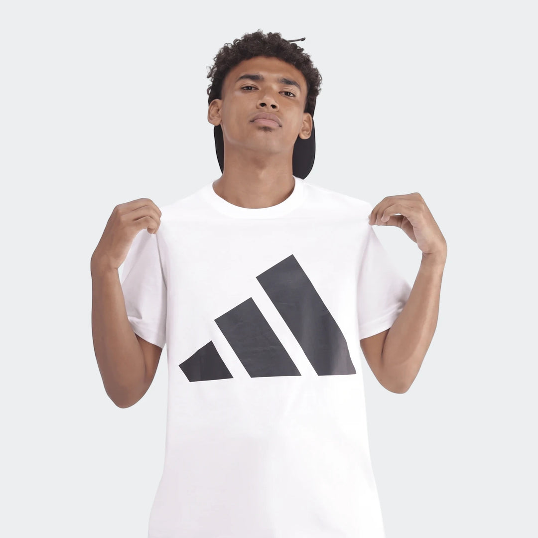 A man wearing a white Sportswear Badge Of Sport T-Shirt with a black logo, shown from the chest up against a gray background.