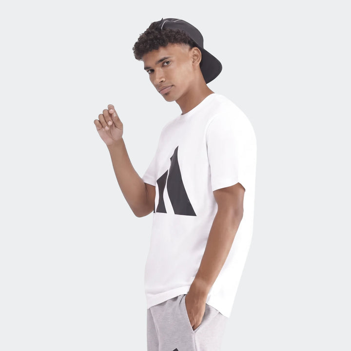 Sportswear Badge Of Sport T-Shirt worn by a male model, white with a black logo, paired with grey sweatpants.