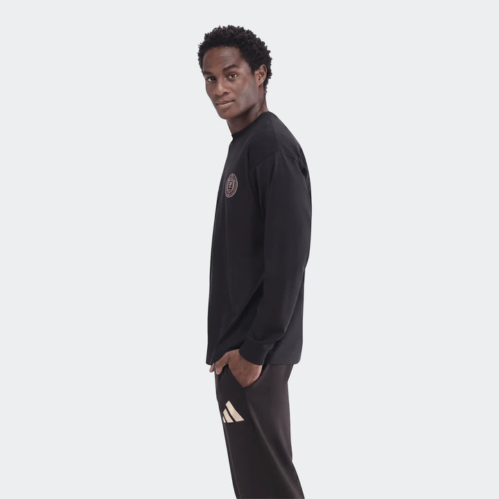 Young man modeling a black Sportswear Open Hem Essentials+ Slim Long Sleeve T-Shirt, paired with black sweatpants with an