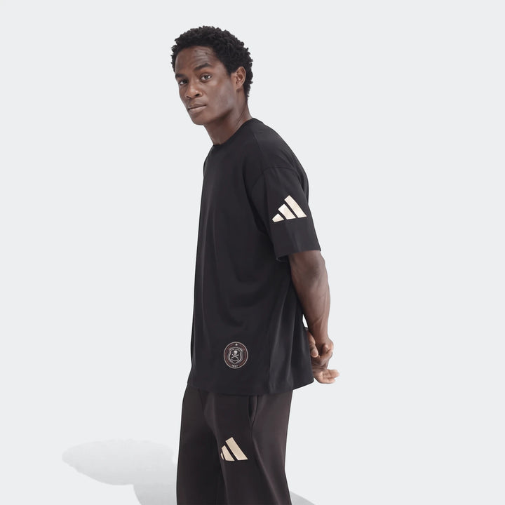 Black Sportswear Open Hem Single Jersey T-Shirt worn by a man, featuring Adidas sleeve stripes and a Pirates badge.