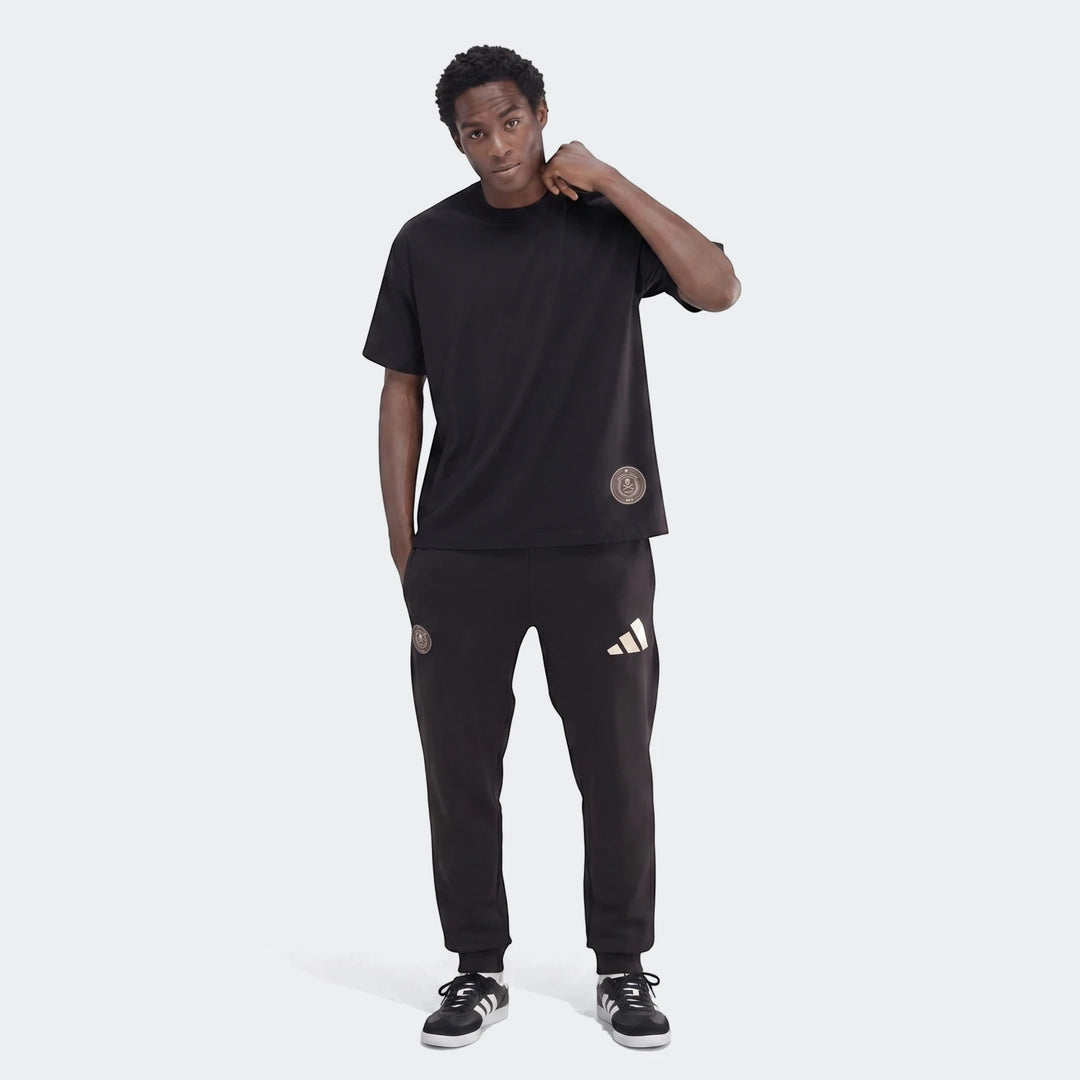 Black Sportswear Open Hem Single Jersey T-Shirt on a male model, paired with black Adidas sweatpants, standing in a studio.