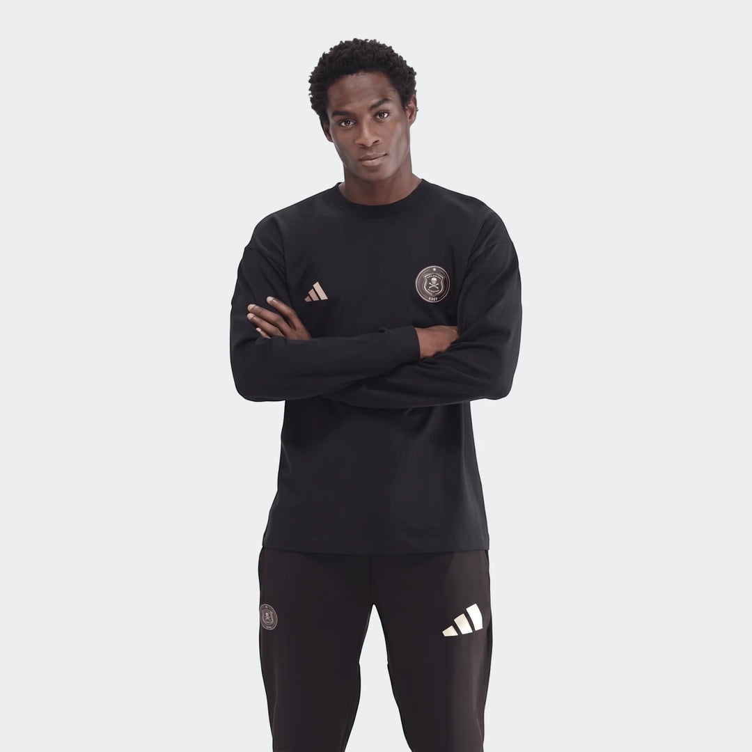 Young man wearing a black Sportswear Open Hem Essentials+ Slim Long Sleeve T-Shirt with Adidas and Orlando Pirates FC logos,