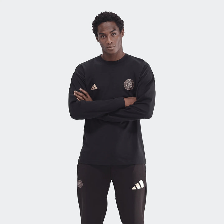 Young man wearing a black Sportswear Open Hem Essentials+ Slim Long Sleeve T-Shirt with Adidas and Orlando Pirates FC logos,
