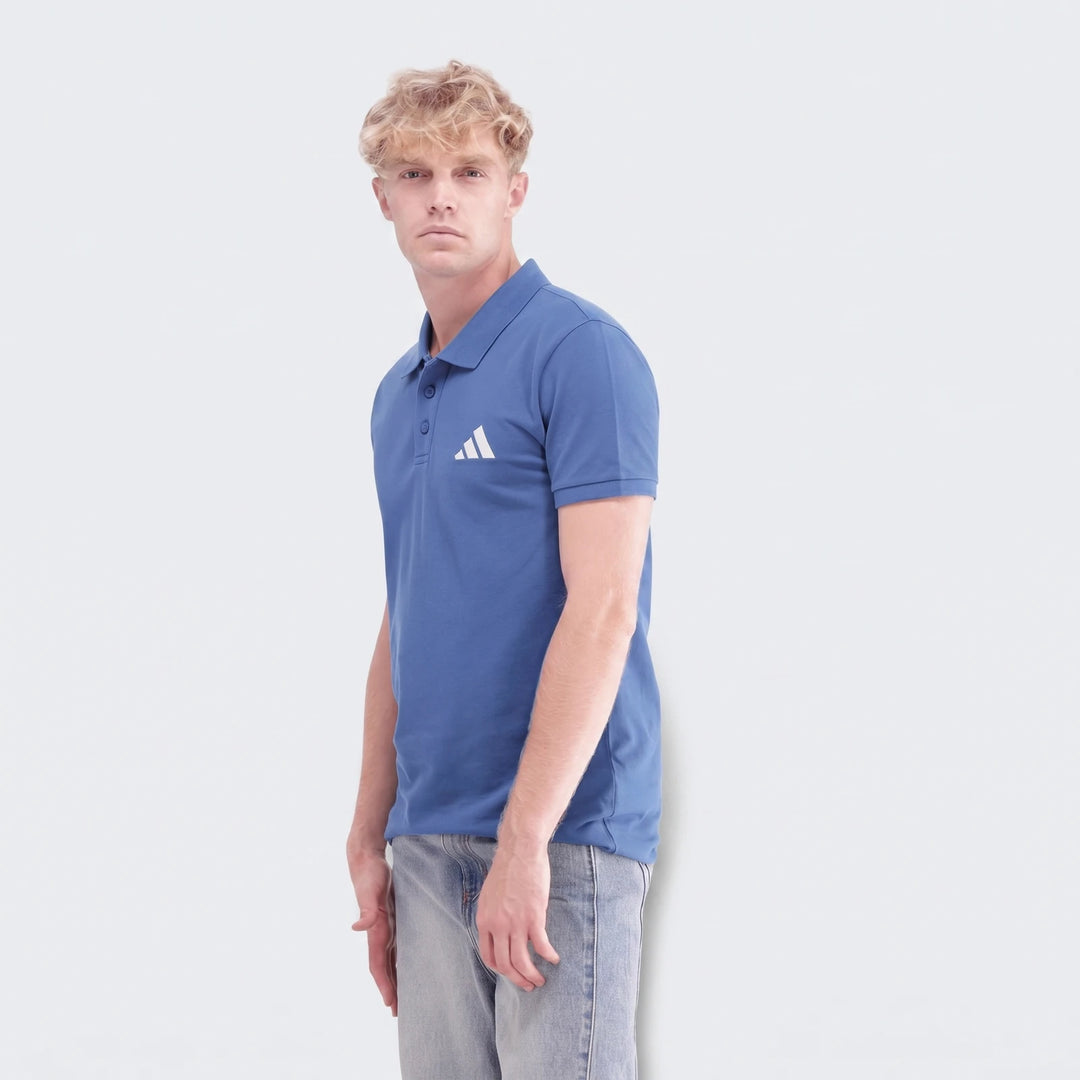 Male model wearing a blue Sportswear Slim Pique Polo Shirt and light wash jeans, captured from the waist up.